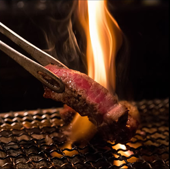 お肉を焼いている様子、トングでお肉をひっくり返している時に、炎が立ち上がっている。